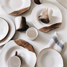 a table topped with white plates and wooden utensils on top of each other