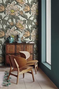 a chair and table in front of a wallpapered room with flowers on it