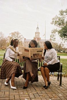 three women sitting on a bench reading newspapers