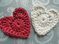 two crocheted hearts sitting next to each other on top of a gray surface