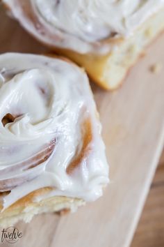 two glazed donuts sitting on top of a wooden cutting board