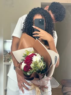 a woman is taking a selfie with her cell phone while holding a bouquet of flowers