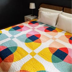 a bed with a colorful quilt on top of it