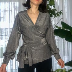 It's our shiny long sleeve v-neck blouse with envelope details. The color is polished silver or we can say metallic color. This blouse produces with made order. It will show the perfect look for every body size. It can be arranged neck decollete. After your order, we start to process. We will get ready to ship in approximately 3-5 days. It is limited to fabric stock. So, we won't promise to make this product when we stock out. You can always ask questions about your size or for any help. Fabric: Elegant V-neck Long Sleeve Top For Winter, Glamorous V-neck Winter Top, Chic Shiny Tops For Fall, Glamorous V-neck Blouse, Chic Silver V-neck Top, Elegant Long Sleeve Top For Fall Party, Elegant Long Sleeve Wrap Top For Work, Chic Long Sleeve Wrap Top For Party, Chic Shiny Blouse For Party