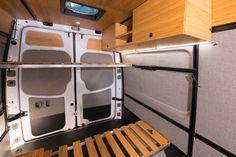 the interior of a small camper with wood flooring and storage compartments on each side