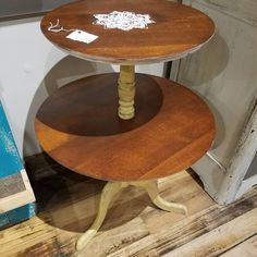 three tiered wooden table sitting on top of a hard wood floor next to a door