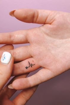 a person with a small tattoo on their left hand holding the finger of another person