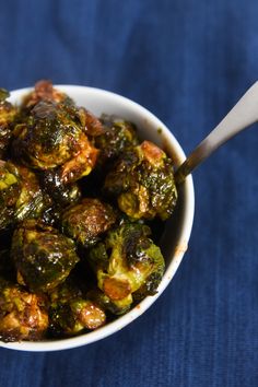 a white bowl filled with cooked brussel sprouts on top of a blue cloth