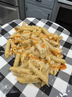 a plate full of pasta and cheese on a checkered tablecloth with an oven in the background