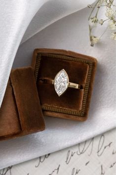 an engagement ring sitting in a velvet box on top of a white cloth covered table