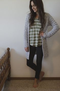 a woman standing in front of a bed wearing black leggings and a striped shirt