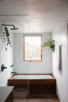 a bath room with a tub a sink and a window on the side of it