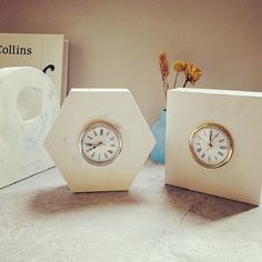 two clocks sitting next to each other on top of a table with flowers in vases