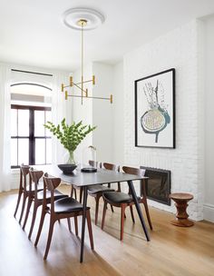 a dining room table with six chairs and a potted plant in the center, next to a fireplace