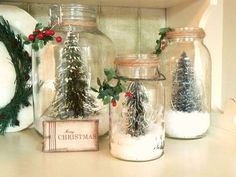 three glass jars filled with snow and christmas decorations