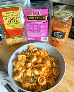 pasta and seasoning are sitting in a bowl on a wooden table next to some spices