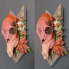 two pieces of art made to look like human skulls with flowers on their heads and in the middle