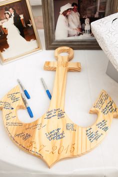 a wooden anchor with writing on it sitting next to two pictures and a pen holder