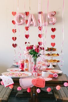 the table is set for valentine's day with pink and red decorations on it