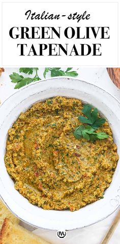 green olive tapenade in a white bowl with bread and parsley on the side