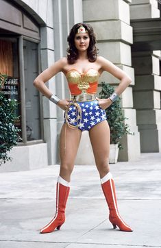 a woman in wonder costume standing on the sidewalk with her hands on her hips and one hand on her hip