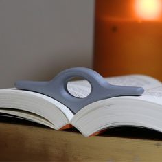 an open book sitting on top of a wooden table next to a lit candle in the background