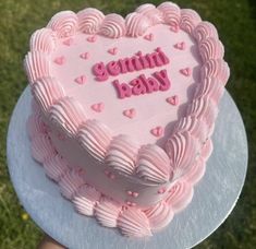 a heart shaped cake with pink frosting on top that says germin baby