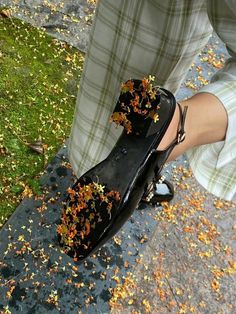 a person standing on the ground with their shoes covered in autumn leaves and flowers,