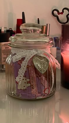 a jar filled with lots of different items on top of a table next to a candle