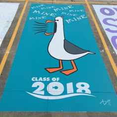 a blue sign with a seagull on it that says class of 2018 painted on the ground