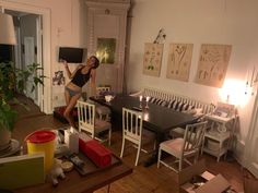 a woman standing in a kitchen next to a dining room table with chairs around it