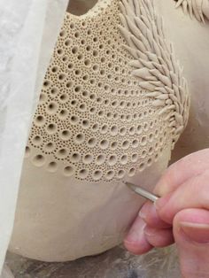 a person working on a clay sculpture with a crochet stitching pattern around it