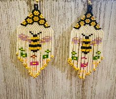 two beaded earrings hanging on a wooden wall