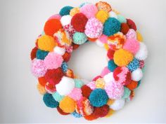 a multicolored wreath with pom - poms hanging from the front wall