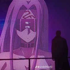 a person standing in front of a large screen with an anime character on it's face