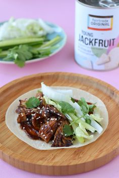 there is a tortilla with meat and lettuce on the plate next to a can of jackfruit