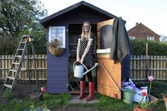 a woman standing in a shed holding a watering can