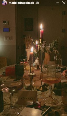 a dining room table is set with wine glasses, candles and other things on it