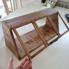 a hand holding a wooden object on top of a table