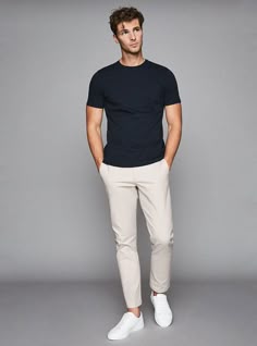 A relaxed yet stylish look with a navy crew neck T-shirt paired with beige chinos and white sneakers. Perfect for achieving a smart-casual vibe that's both comfortable and fashionable for any day activity. Chinos Men Outfit, Smart Casual Menswear, Shirt Outfit Men, Mens Summer Outfits