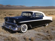 an old black and white car parked in the desert