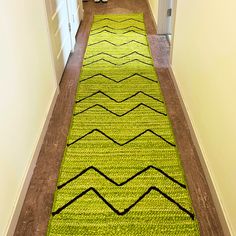 a long hallway with a green rug on the floor and white doors in the background