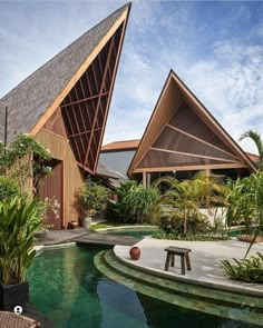 an outdoor swimming pool surrounded by plants and wooden structures that are shaped like triangulars