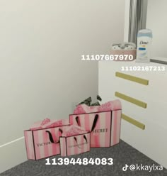 three pink bags sitting on the floor in front of a white dresser with gold handles