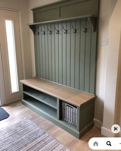 a wooden bench sitting in the middle of a living room next to a door with hooks on it