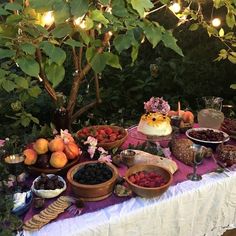 a table topped with lots of food and fruit on top of a white table cloth