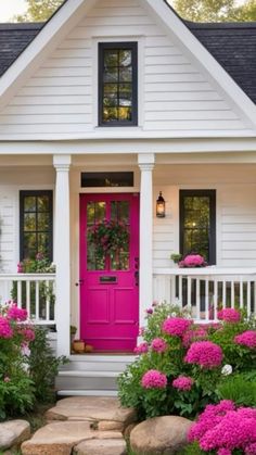 a white house with pink front door and flowers