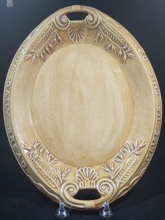 a brown plate with an ornate design on the front and sides, sitting on a black surface