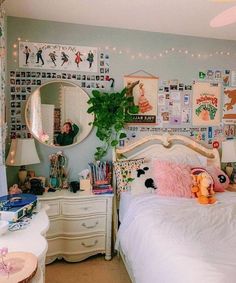 a bedroom decorated in pastel colors with lots of pictures on the walls and furniture