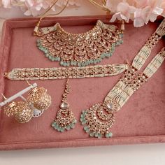 an assortment of jewelry is displayed on a pink tray